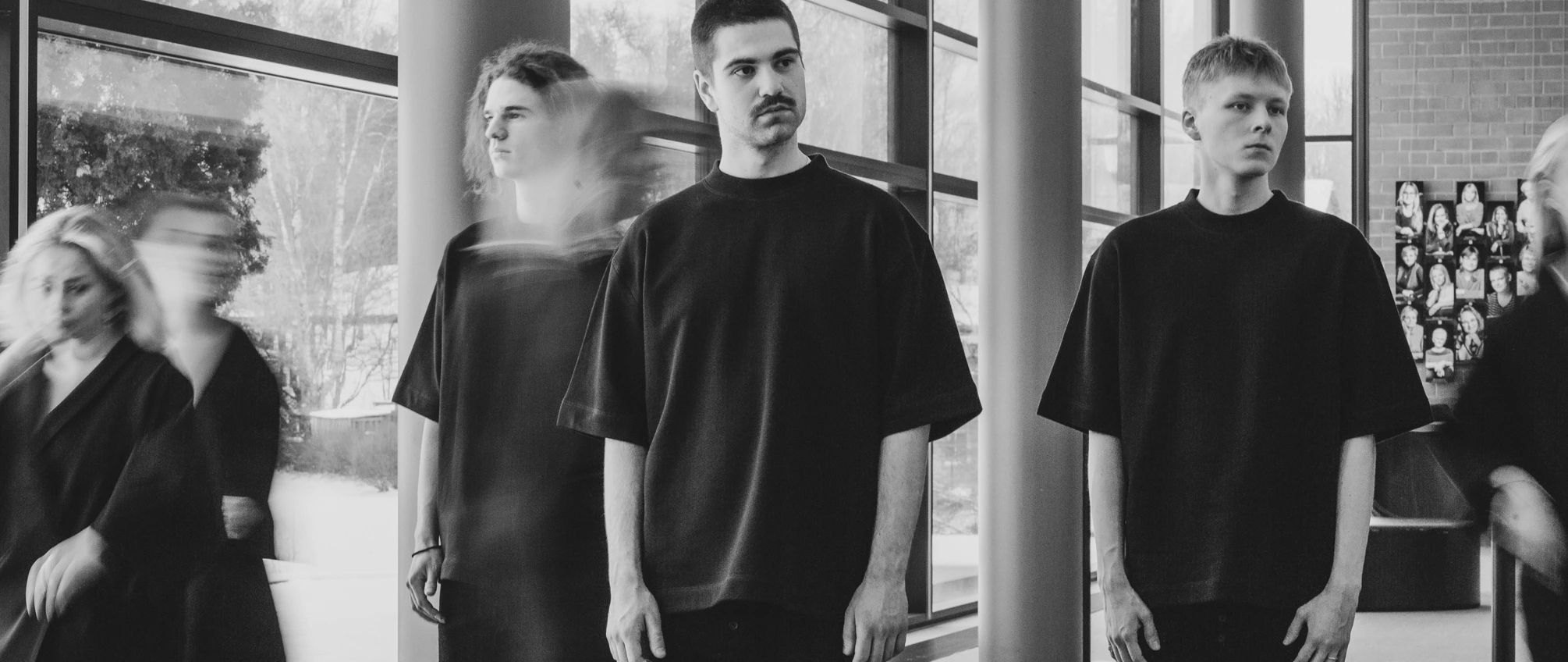 Four people wearing dark UPMADE garments in a bright studio